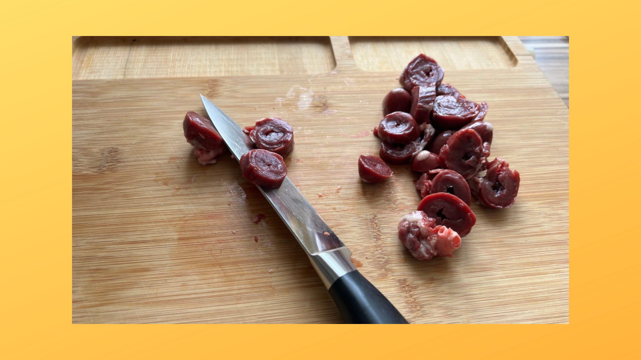 Putenherzen auf einemHolzbrett werden mit einem scharfen Messer in Scheiben geschnitten